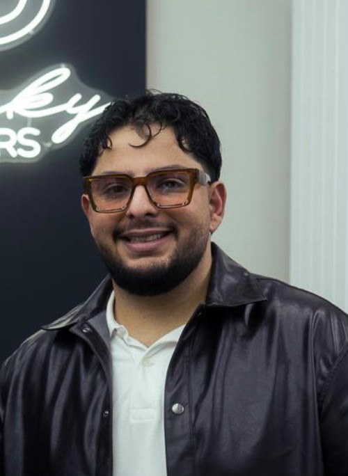 Kaan Yigit vor dem Peaky-Barbers-Neonschild